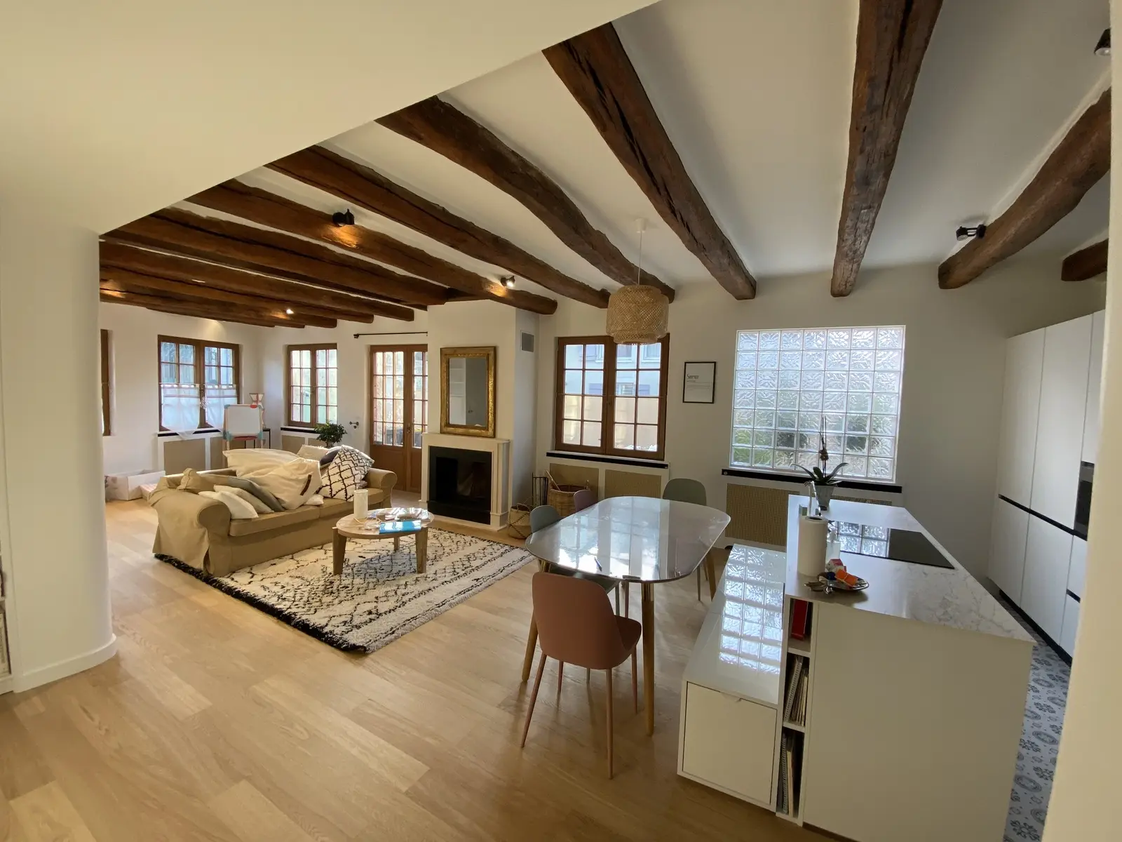 Photo d'un intérieur rénové dont le charme réside dans ses poutres apparentes. Ces poutres en bois, d'une teinte marron chaleureuse, ont été soigneusement mises en valeur par une peinture et un traitement récent. Elles contrastent agréablement avec le plafond blanc et illuminent l'espace, témoignant d'un travail de rénovation soigné qui a su préserver et sublimer le cachet rustique de la pièce.